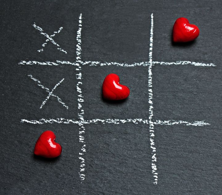 Three Heart-shaped Red Stones Placed on Tic-tac-toe Game Bord