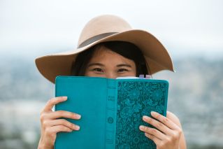 Woman in Brown Sun Hat Holding Blue Book